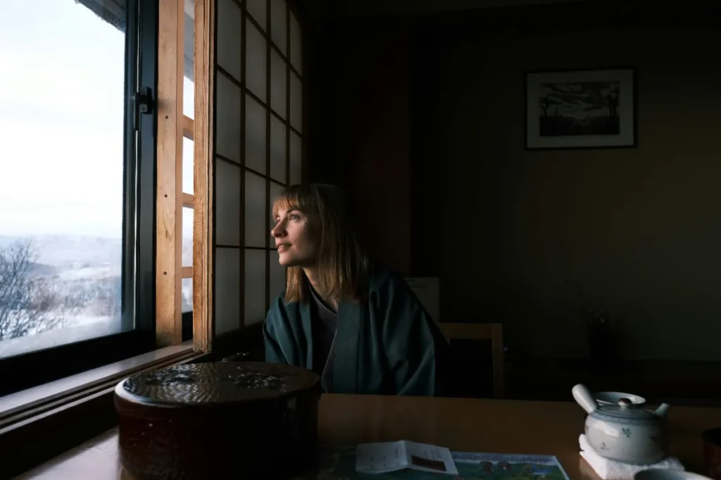 和室から窓の外を眺める女性