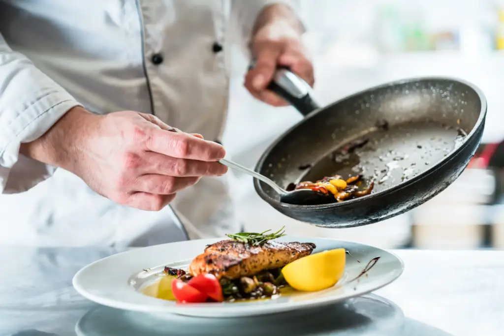 レストランの厨房で料理の仕上げをするシェフ